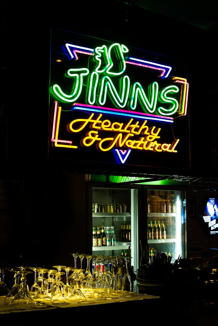 Vibrant neon sign in a bar with illuminated cocktail glasses and beverages.