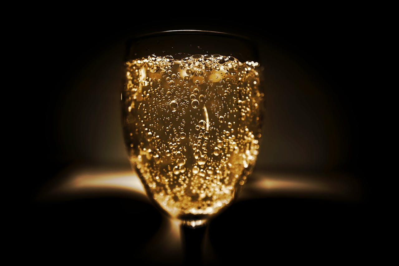 Elegant close-up of a champagne glass with bubbles against a dark background, perfect for celebrations.